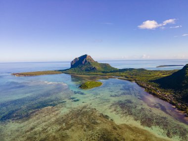 Le Morne plajı Mauritius, Tropikal plaj palmiye ağaçları ve beyaz kum mavisi okyanus ve şemsiyeli plaj yatakları, güneş sandalyeleri ve güneş şemsiyeleri bir palmiye ağacının altında, Le Morne plajı Mauritius 'ta.