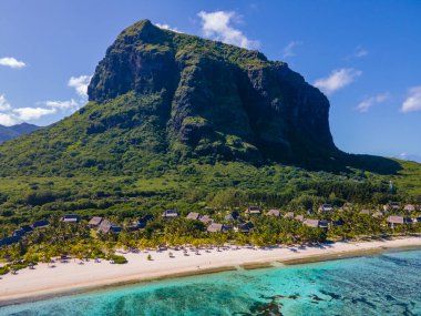 Le Morne beach Mauritius,Tropical beach with palm trees and white sand blue ocean and beach beds with umbrella,Sun chairs and parasol under a palm tree at a tropical beac, Le Morne beach Mauritius