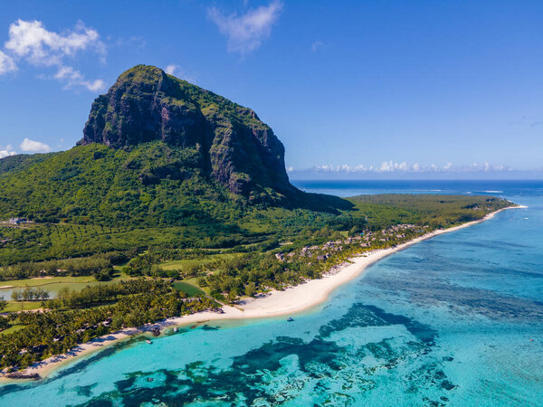 Le Morne beach Mauritius,Tropical beach with palm trees and white sand blue ocean and beach beds with umbrella,Sun chairs and parasol under a palm tree at a tropical beac, Le Morne beach Mauritius
