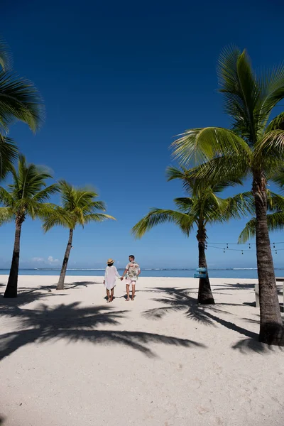 Le Morne praia Maurício, praia tropical com palmeiras e areia branca mar azul casal homens e mulheres andando na praia durante as férias — Fotografia de Stock