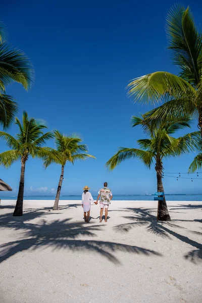 Le Morne beach Mauritius,Tropical beach with palm trees and white sand blue ocean couple men and woman walking at the beach during vacation — Fotografia de Stock