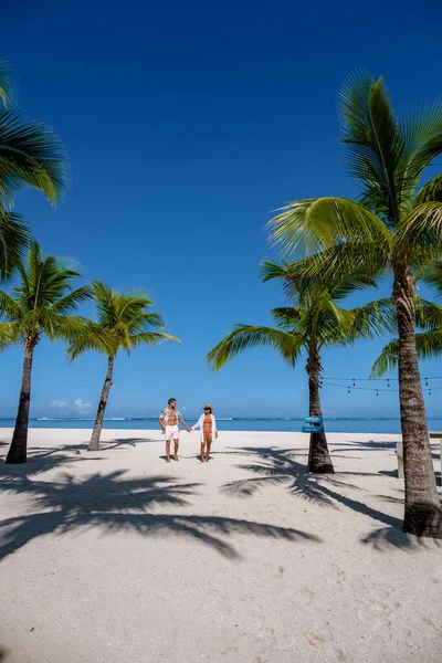 Le Morne praia Maurício, praia tropical com palmeiras e areia branca mar azul casal homens e mulheres andando na praia durante as férias — Fotografia de Stock