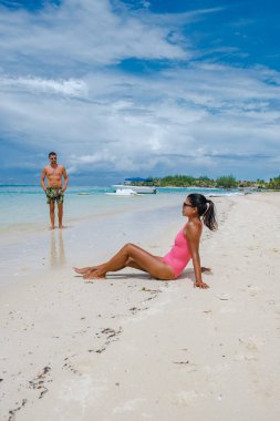 Le Morne plajı Mauritius, Tropikal plaj palmiye ağaçları ve beyaz kum mavisi okyanus. Tatil sırasında sahilde yürüyen çift ve kadın.