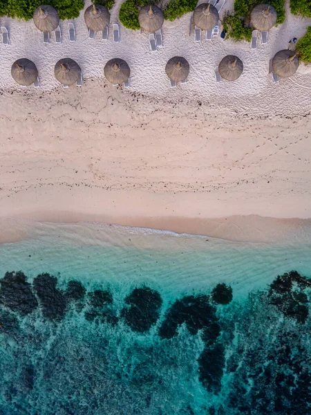 Le Morne beach Mauritius,Tropical beach with palm trees and white sand blue ocean and beach beds with umbrella,Sun chairs and parasol under a palm tree at a tropical beac, Le Morne beach Mauritius Stock Photo