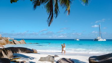 Praslin Seyşeller tropikal adasında plajlar ve palmiye ağaçları var. Orta yaşlı birkaç erkek ve kadın tatilde Seyşeller 'de Anse Lazio Praslin Seyşeller' in tropik plajını ziyaret ediyor.