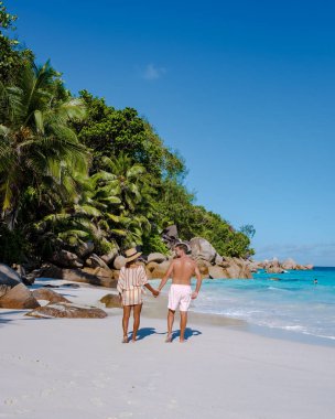 Praslin Seyşeller tropikal adasında plajlar ve palmiye ağaçları var. Orta yaşlı birkaç erkek ve kadın tatilde Seyşeller 'de Anse Lazio Praslin Seyşeller' in tropik plajını ziyaret ediyor.