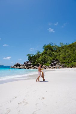 Praslin Seyşeller tropikal adasında plajlar ve palmiye ağaçları var. Orta yaşlı birkaç erkek ve kadın tatilde Seyşeller 'de Anse Lazio Praslin Seyşeller' in tropik plajını ziyaret ediyor.