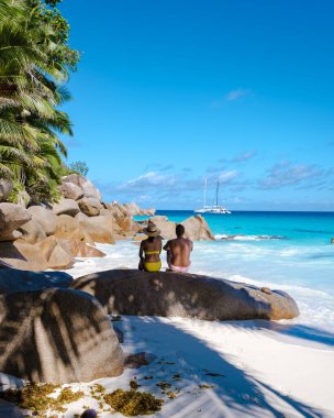 Praslin Seyşeller tropikal adasında plajlar ve palmiye ağaçları var. Orta yaşlı birkaç erkek ve kadın tatilde Seyşeller 'de Anse Lazio Praslin Seyşeller' in tropik plajını ziyaret ediyor.
