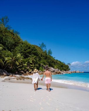 Praslin Seyşeller tropikal adasında plajlar ve palmiye ağaçları var. Orta yaşlı birkaç erkek ve kadın tatilde Seyşeller 'de Anse Lazio Praslin Seyşeller' in tropik plajını ziyaret ediyor.