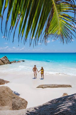 Praslin Seyşeller tropikal adasında plajlar ve palmiye ağaçları var. Orta yaşlı birkaç erkek ve kadın tatilde Seyşeller 'de Anse Lazio Praslin Seyşeller' in tropik plajını ziyaret ediyor.
