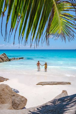 Praslin Seyşeller tropikal adasında plajlar ve palmiye ağaçları var. Orta yaşlı birkaç erkek ve kadın tatilde Seyşeller 'de Anse Lazio Praslin Seyşeller' in tropik plajını ziyaret ediyor.