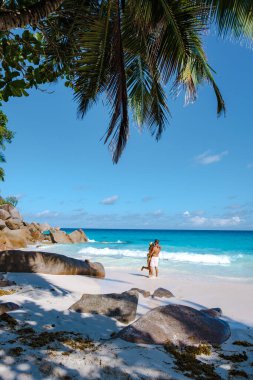 Praslin Seyşeller tropikal adasında plajlar ve palmiye ağaçları var. Orta yaşlı birkaç erkek ve kadın tatilde Seyşeller 'de Anse Lazio Praslin Seyşeller' in tropik plajını ziyaret ediyor.