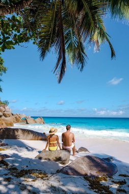 Praslin Seyşeller tropikal adasında plajlar ve palmiye ağaçları var. Orta yaşlı birkaç erkek ve kadın tatilde Seyşeller 'de Anse Lazio Praslin Seyşeller' in tropik plajını ziyaret ediyor.