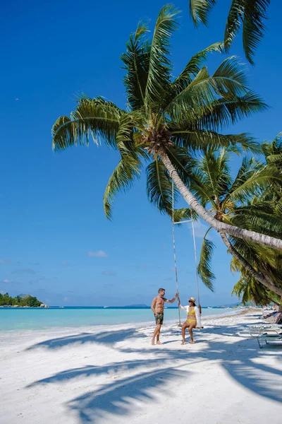 Praslin Seychellen tropisch eiland met withe stranden en palmbomen, paar mannen en vrouwen in hangmat schommel op het strand onder een palmboom bij Anse Volber Seychellen — Stockfoto