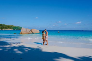 Praslin Seyşeller tropikal adasında plajlar ve palmiye ağaçları var. Orta yaşlı birkaç erkek ve kadın tatilde Seyşeller 'de Anse Lazio Praslin Seyşeller' in tropik plajını ziyaret ediyor.