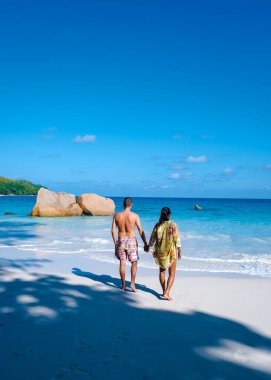 Praslin Seyşeller tropikal adasında plajlar ve palmiye ağaçları var. Orta yaşlı birkaç erkek ve kadın tatilde Seyşeller 'de Anse Lazio Praslin Seyşeller' in tropik plajını ziyaret ediyor.