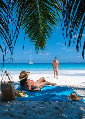 Praslin Seyşeller tropikal adasında plajlar ve palmiye ağaçları var. Orta yaşlı birkaç erkek ve kadın tatilde Seyşeller 'de Anse Lazio Praslin Seyşeller' in tropik plajını ziyaret ediyor.