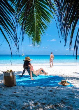 Praslin Seyşeller tropikal adasında plajlar ve palmiye ağaçları var. Seyşeller 'de tatilde olan iki erkek ve kadın. Anse Lazio Praslin Seyşeller' in tropik plajını ziyaret ediyorlar.. 