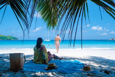 Praslin Seyşeller tropikal adasında plajlar ve palmiye ağaçları var. Seyşeller 'de tatilde olan iki erkek ve kadın. Anse Lazio Praslin Seyşeller' in tropik plajını ziyaret ediyorlar.. 