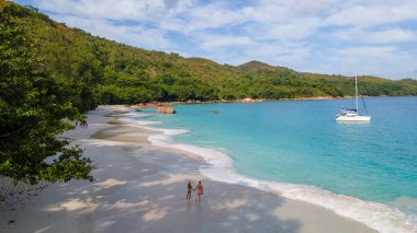 Praslin Seyşeller tropikal adasında plajlar ve palmiye ağaçları var. Seyşeller 'de tatilde olan iki erkek ve kadın. Anse Lazio Praslin Seyşeller' in tropik plajını ziyaret ediyorlar.. 
