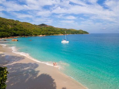 Praslin Seychelles tropical island with withe beaches and palm trees, couple of men and women mid age on vacation at Seychelles visiting the tropical beach of Anse Lazio Praslin Seychelles. 