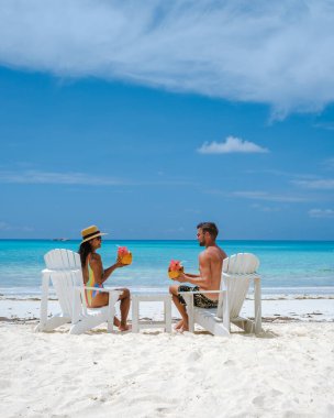 couple men and women on the beach with coconut drink Praslin Seychelles tropical island with withe beaches and palm trees, the beach of Anse Volbert Seychelles.  clipart