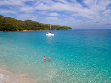 Praslin Seyşeller tropikal adasında plajlar ve palmiye ağaçları var. Seyşeller 'de tatilde olan iki erkek ve kadın. Anse Lazio Praslin Seyşeller' in tropik plajını ziyaret ediyorlar.. 