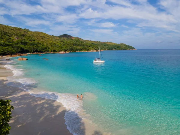Praslin Seyşeller tropikal adasında plajlar ve palmiye ağaçları var. Seyşeller 'de tatilde olan iki erkek ve kadın. Anse Lazio Praslin Seyşeller' in tropik plajını ziyaret ediyorlar.. 