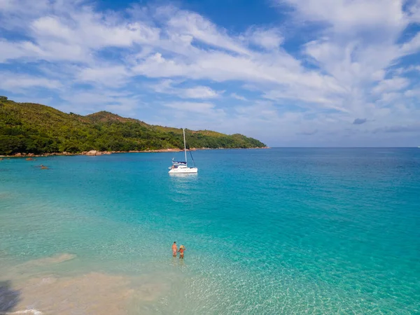 Praslin Seyşeller tropikal adasında plajlar ve palmiye ağaçları var. Seyşeller 'de tatilde olan iki erkek ve kadın. Anse Lazio Praslin Seyşeller' in tropik plajını ziyaret ediyorlar.. 