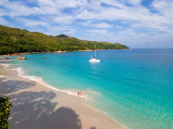 Praslin Seyşeller tropikal adasında plajlar ve palmiye ağaçları var. Seyşeller 'de tatilde olan iki erkek ve kadın. Anse Lazio Praslin Seyşeller' in tropik plajını ziyaret ediyorlar.. 