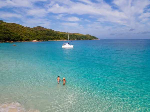 Praslin Seyşeller tropikal adasında plajlar ve palmiye ağaçları var. Seyşeller 'de tatilde olan iki erkek ve kadın. Anse Lazio Praslin Seyşeller' in tropik plajını ziyaret ediyorlar.. 
