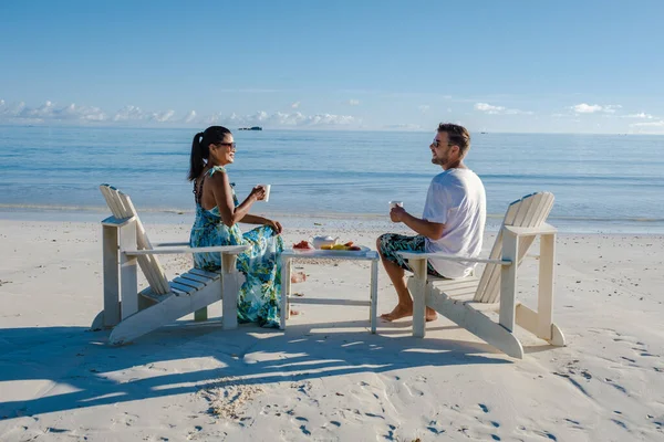 在海滩上享用咖啡和水果作为早餐的男女情侣，在塞舌尔的普拉斯林热带岛屿上享用海滩和棕榈树，在塞舌尔的安塞沃尔伯特海滩 — 图库照片