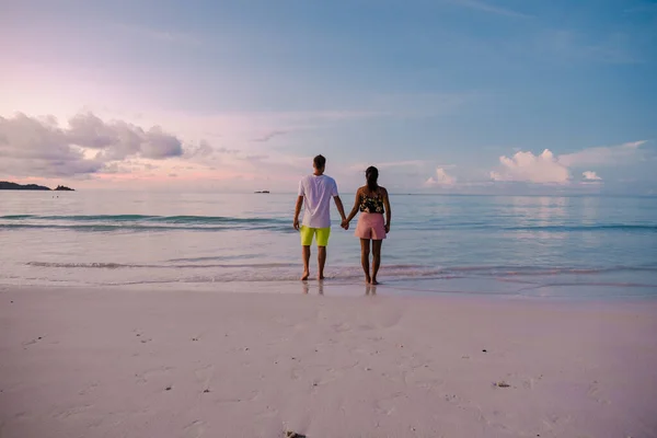 Praslin Seychelles tropical island with withe beaches and palm trees, couple men and women mid age on vacation at the Seychelles watching sunset at the ocean — Foto de Stock