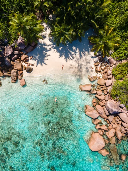 Praslin Seychelles เกาะเขตร้อนที่มีชายหาดและต้นปาล์มคู่ชายและหญิงวัยกลางวันในวันหยุดที่ Seychelles เยี่ยมชมชายหาดเขตร้อนของ Anse Lazio Praslin Seychelles drone view — ภาพถ่ายสต็อก