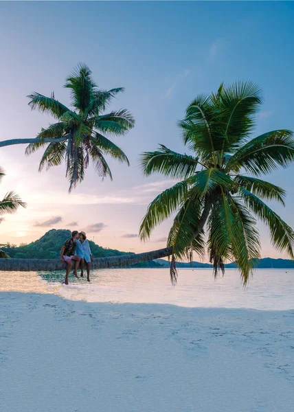 Praslin Seychelles tropical island with withe beaches and palm trees, couple men and woman with palmtree watching sunset — Zdjęcie stockowe