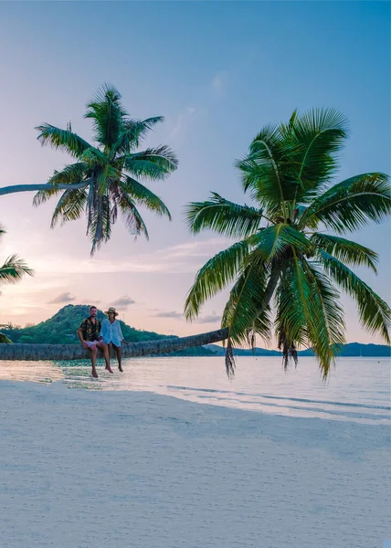 Praslin Seychelles tropical island with withe beaches and palm trees, couple men and woman with palmtree watching sunset — Stockfoto