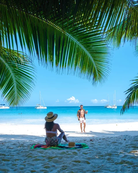 ビーチやヤシの木があるプラスリンセイシェル熱帯の島、 Anseラツィオの熱帯ビーチを訪れるセーシェルでの休暇中のカップルの男性と女性プラスリンセイシェルのドローンビュー — ストック写真