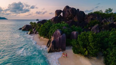 Anse Source dArgent plajı, La Digue Adası, Seyshelles, İHA hava görüntüsü La Digue Seyşelles kuş bakışı, gün batımında sahilde yürüyen birkaç erkek ve kadın lüks bir tatilde