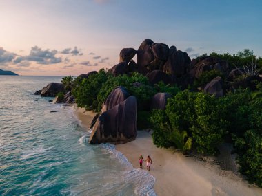 Anse Source dArgent plajı, La Digue Adası, Seyshelles, İHA hava görüntüsü La Digue Seyşelles kuş bakışı, gün batımında sahilde yürüyen birkaç erkek ve kadın lüks bir tatilde