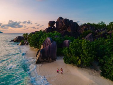 Anse Source dArgent plajı, La Digue Adası, Seyshelles, İHA hava görüntüsü La Digue Seyşelles kuş bakışı, gün batımında sahilde yürüyen birkaç erkek ve kadın lüks bir tatilde