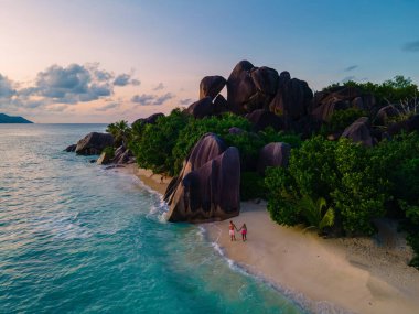 Anse Source dArgent plajı, La Digue Adası, Seyshelles, İHA hava görüntüsü La Digue Seyşelles kuş bakışı, gün batımında sahilde yürüyen birkaç erkek ve kadın lüks bir tatilde