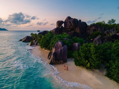Anse Source dArgent plajı, La Digue Adası, Seyshelles, İHA hava görüntüsü La Digue Seyşelles kuş bakışı, gün batımında sahilde yürüyen birkaç erkek ve kadın lüks bir tatilde