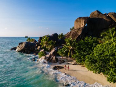 Anse Source dArgent beach, La Digue Island, Seyshelles, Drone aerial view of La Digue Seychelles bird eye view, couple men and woman walking at the beach during sunset at a luxury vacation