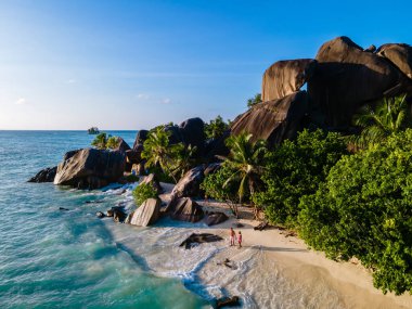 Anse Source dArgent plajı, La Digue Adası, Seyshelles, İHA hava görüntüsü La Digue Seyşelles kuş bakışı, gün batımında sahilde yürüyen birkaç erkek ve kadın lüks bir tatilde