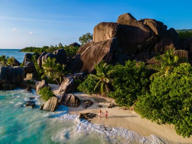 Anse Source dArgent plajı, La Digue Adası, Seyshelles, İHA hava görüntüsü La Digue Seyşelles kuş bakışı, gün batımında sahilde yürüyen birkaç erkek ve kadın lüks bir tatilde