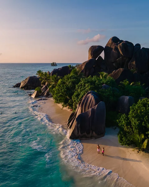 Anse Source dArgent plajı, La Digue Adası, Seyshelles, İHA hava görüntüsü La Digue Seyşelles kuş bakışı, gün batımında sahilde yürüyen birkaç erkek ve kadın lüks bir tatilde
