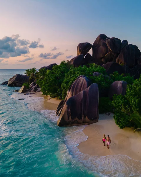 Anse Source dArgent plajı, La Digue Adası, Seyshelles, İHA hava görüntüsü La Digue Seyşelles kuş bakışı, gün batımında sahilde yürüyen birkaç erkek ve kadın lüks bir tatilde