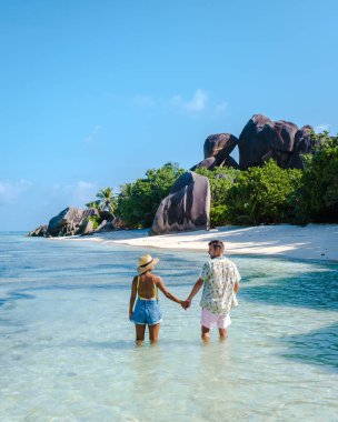 Anse Source dArgent plajı, La Digue Adası, Seyshelles, İHA hava görüntüsü La Digue Seyşelles kuş bakışı, gün batımında sahilde yürüyen birkaç erkek ve kadın lüks bir tatilde