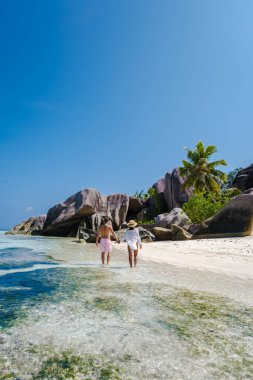 Anse Source dArgent plajı, La Digue Adası, Seyshelles, İHA hava görüntüsü La Digue Seyşelles kuş bakışı, gün batımında sahilde yürüyen birkaç erkek ve kadın lüks bir tatilde