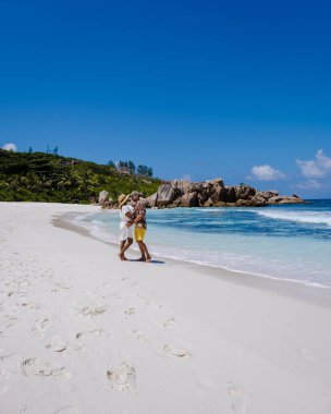 Anse Cocos plajı, La Digue Adası, Seyshelles, La Digue Seychelles kuş bakışı drone görüntüsü, günbatımında kumsalda yürüyen birkaç erkek ve kadın lüks bir tatilde.